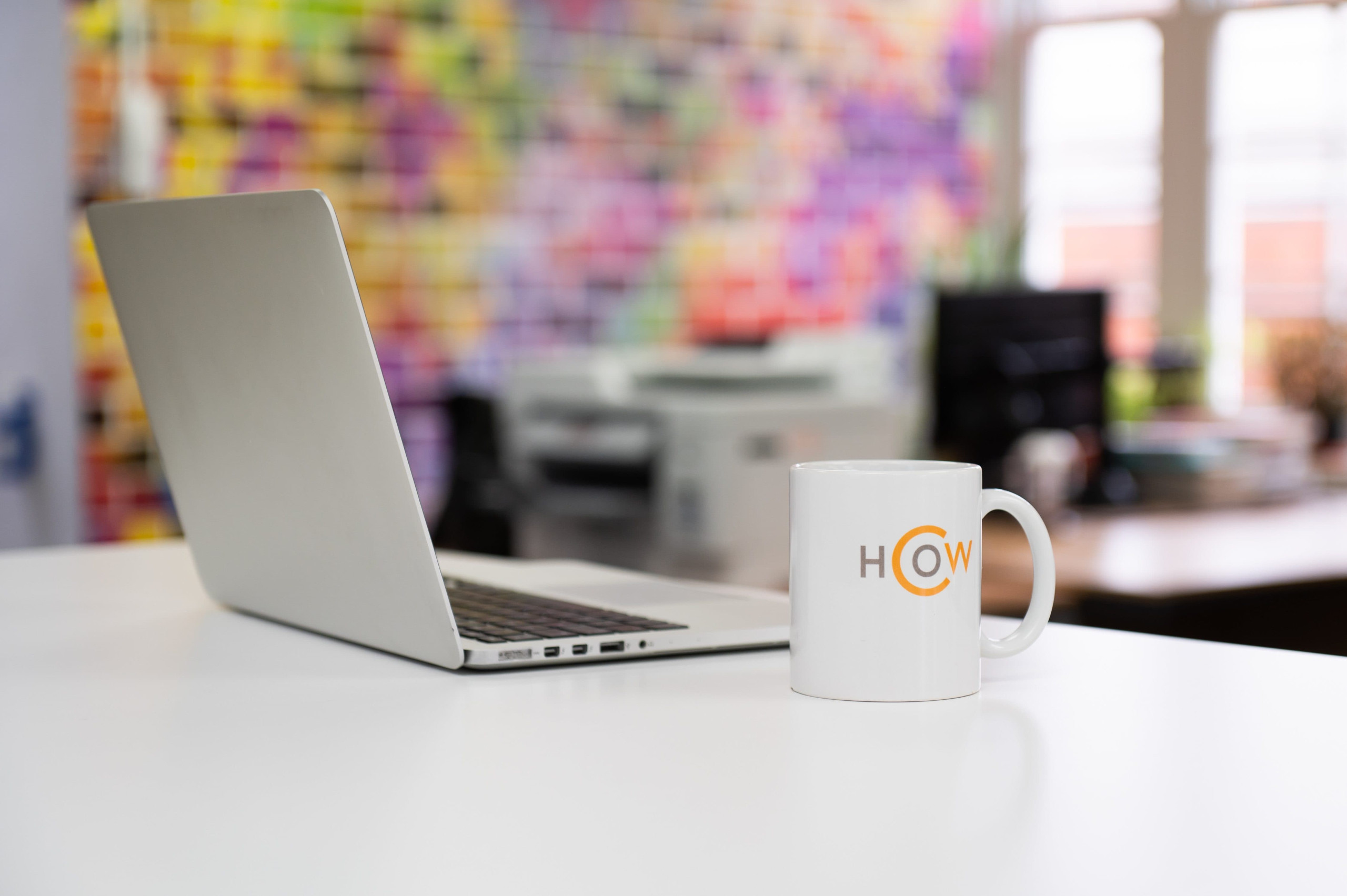 A laptop and coffee mug on a white desk