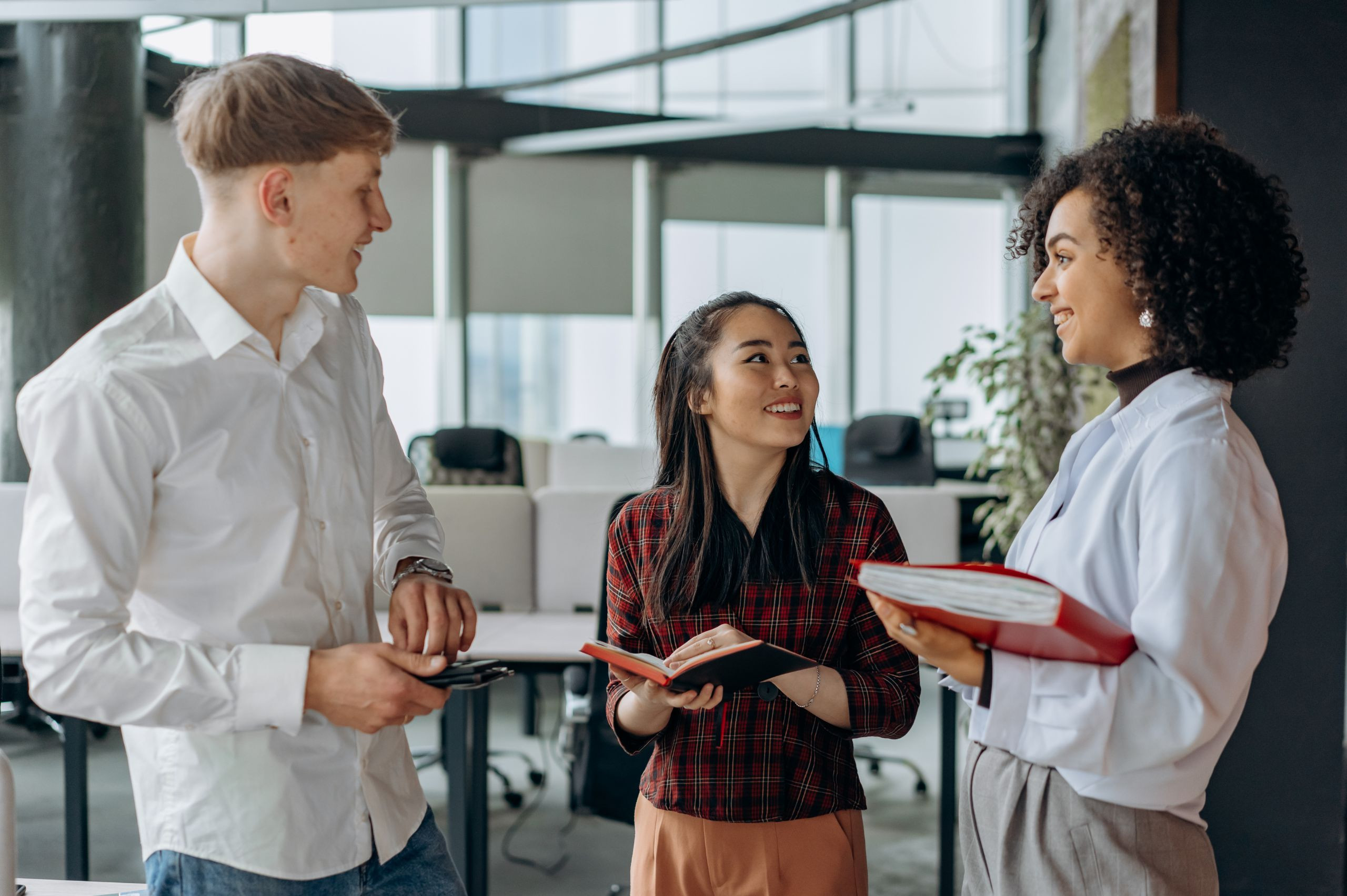 one man and 2 women talking in a work environment