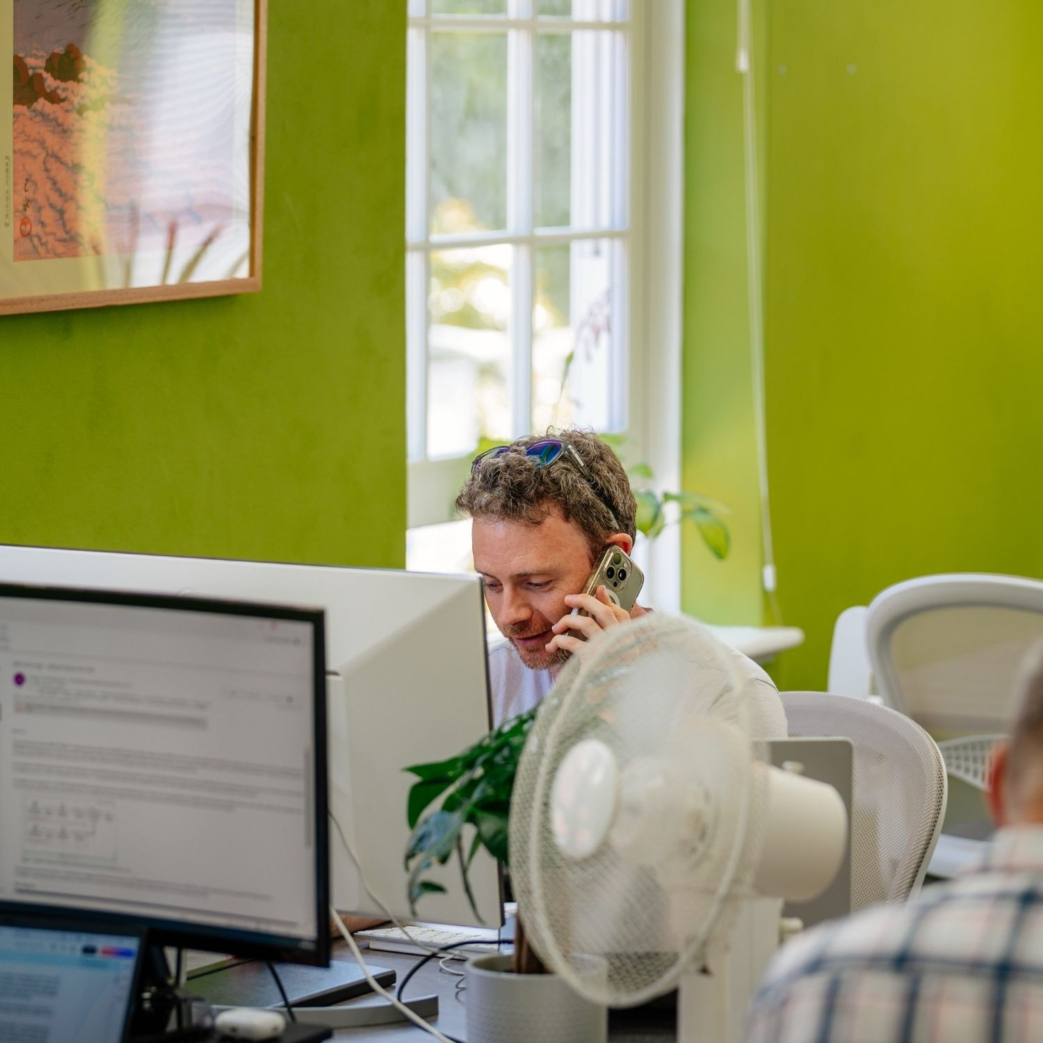 man taking a phone call at a work desk in a coworking space