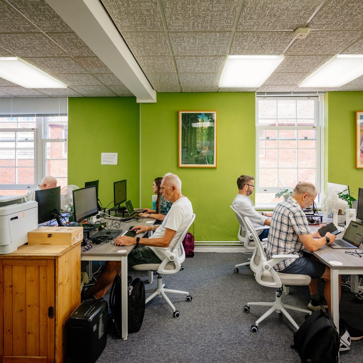 Men and women working at desks in a coworking space
