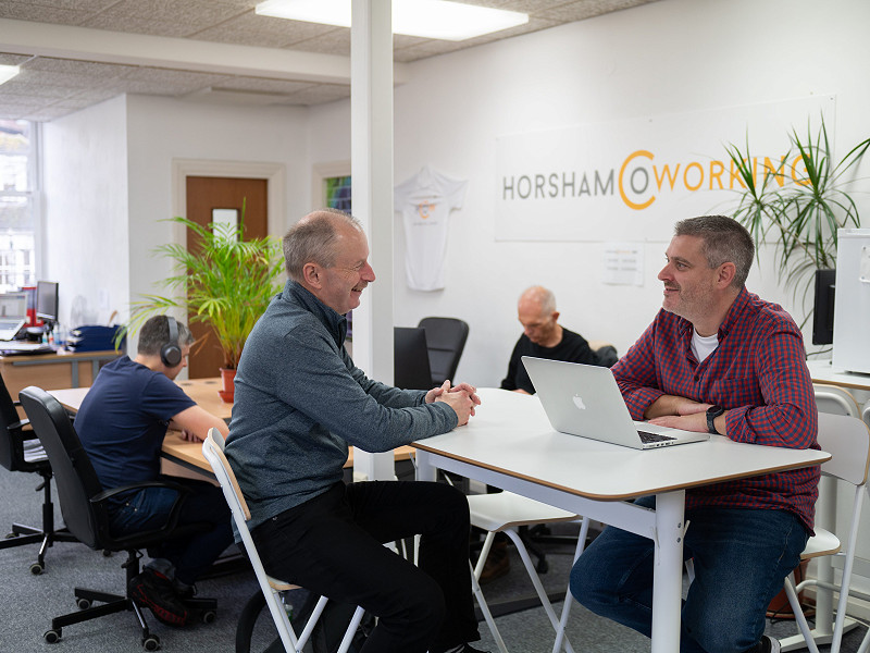 Two people sitting and chatting at a table in Horsham Coworking