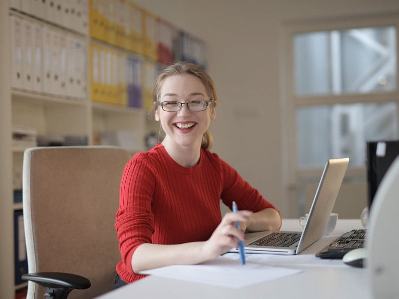 A woman at a desk in front of a laptop and smiling