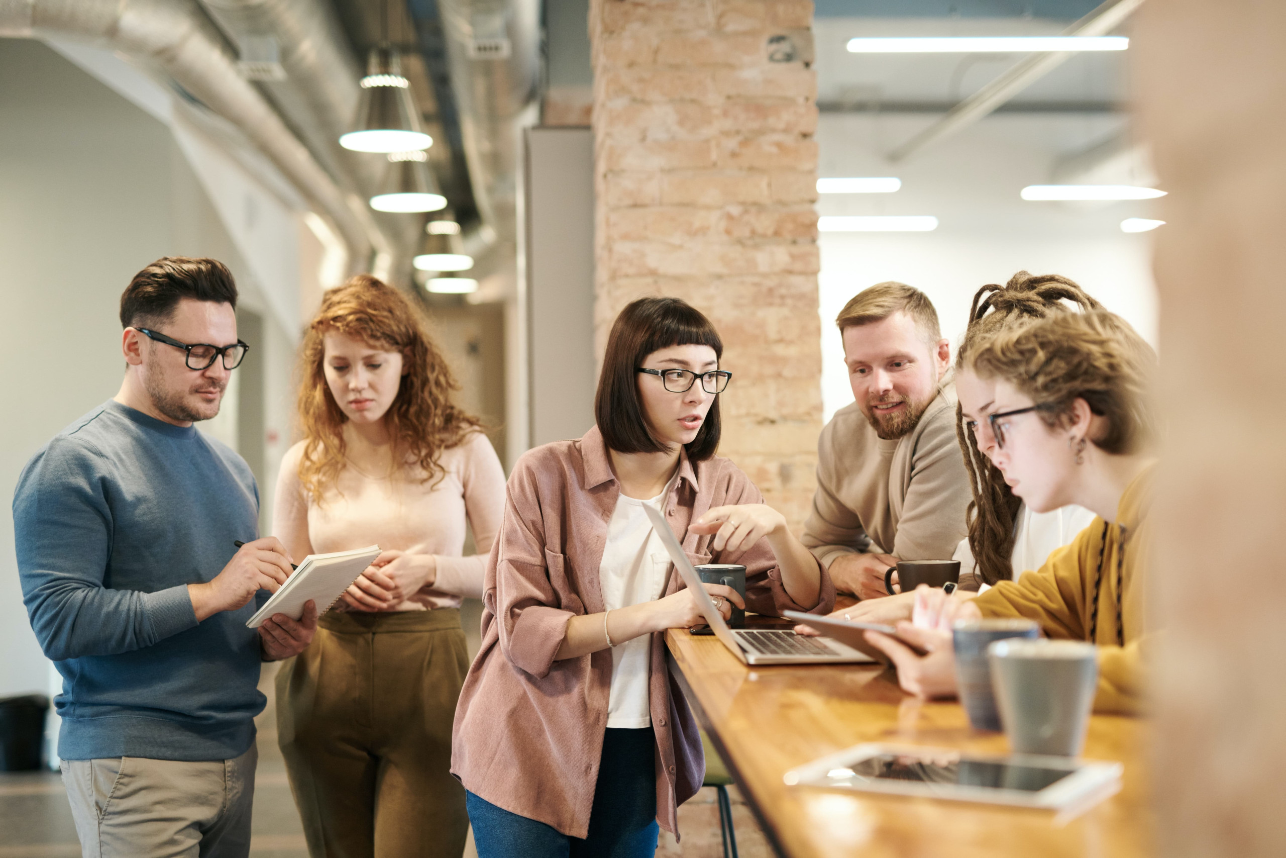 A group of people gathered round a laptop and tablet PC