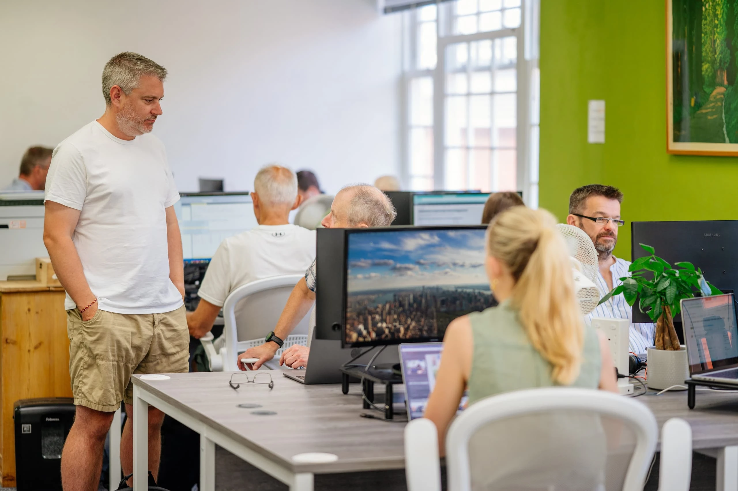 Matt and Clive talking in the Horsham Coworking office while others work at their desks