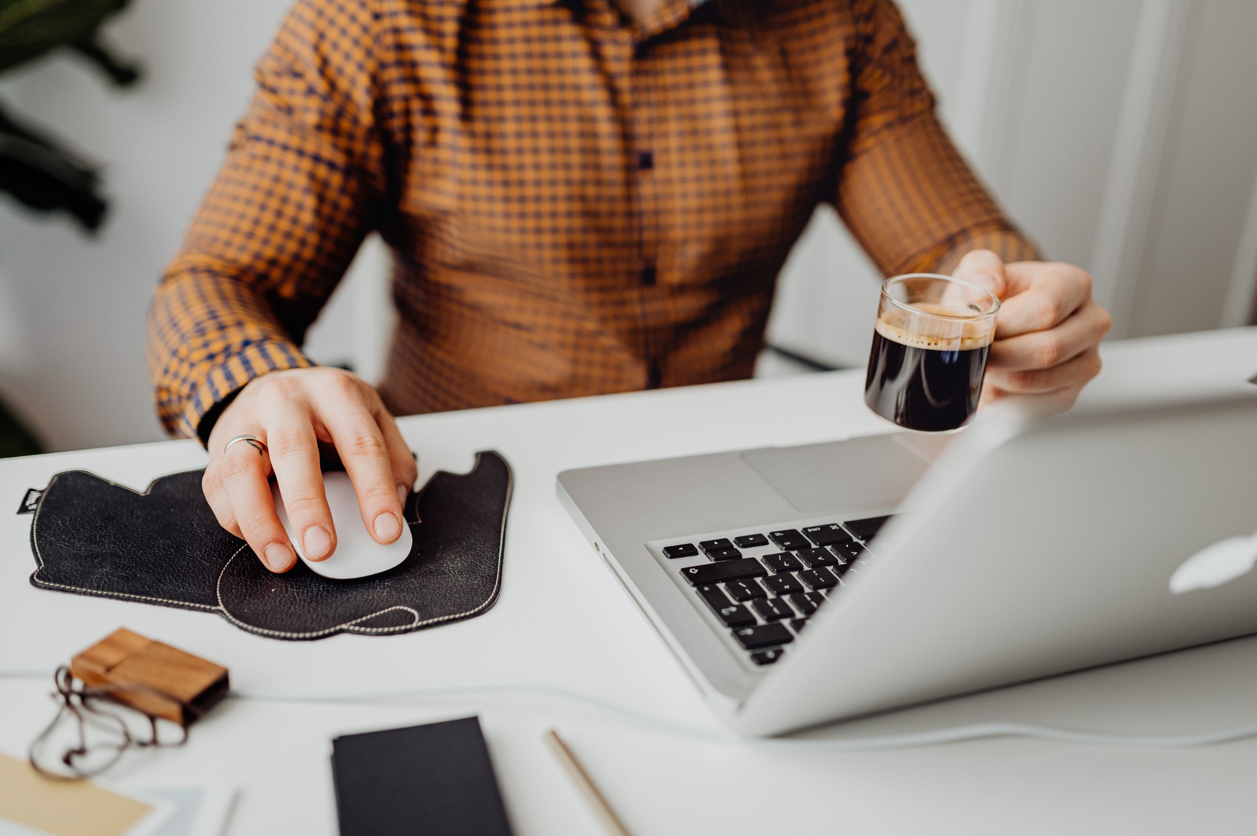 man working at desk on laptop holding a cup of coffee