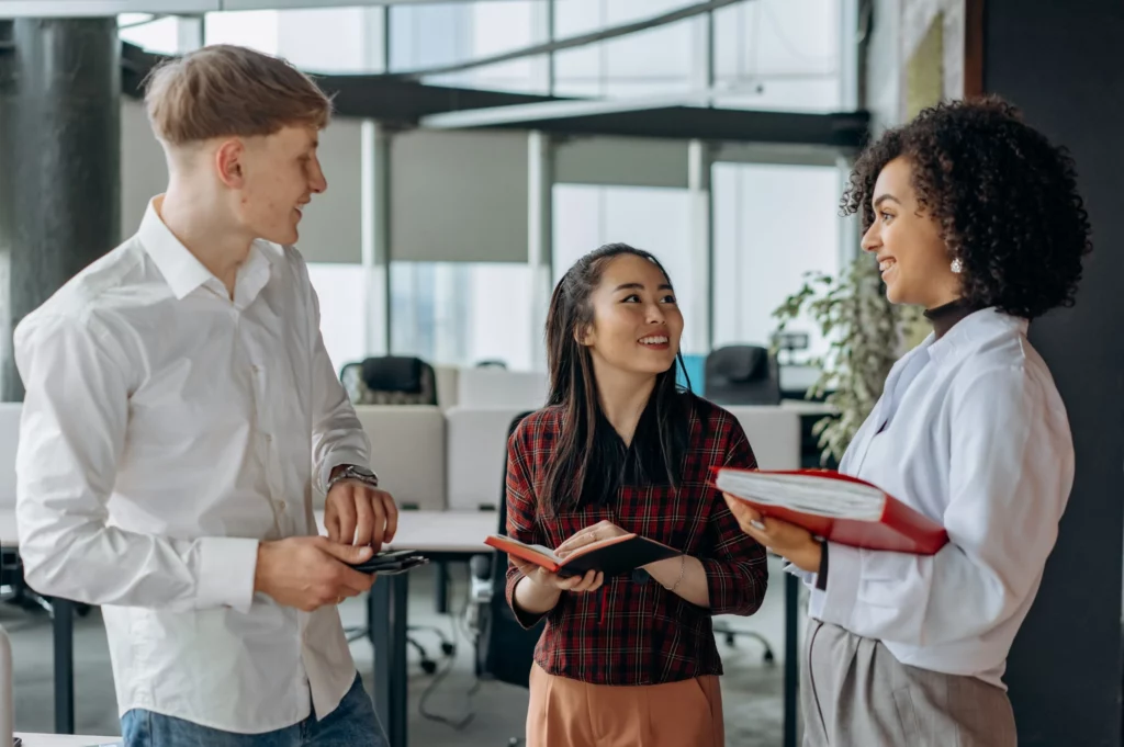 one man and 2 women talking in a work environment